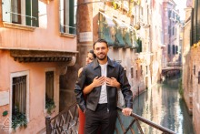 The couple holds each other atop a picturesque bridge over the canals of Venice, Italy, their embrace echoing the timeless elegance of this romantic venue known for its scenic waterways and historic ambiance.