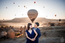 In Cappadocia, Turkey, a couple poses against the surreal landscapes of Goreme, Nevsehir, their pre-wedding session capturing the dramatic rock formations and expansive skies of this iconic region.