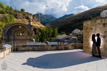 At Iglesia de Santa María in Cazorla, Jaén, Spain, the couple is silhouetted against a backlit stone wall, their figures softly outlined in the spotlight, surrounded by the atmospheric charm of this old world setting.