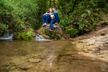 Sitting Peacefully Beside A Waterfall In Cazorla, Spain, This Couple’s Engagement Portrait Is Surrounded By Nature Sitting together on a large boulder beside a small waterfall and clear pool along Sendero del Río Cerezuelo in Cazorla, Jaén, Spain, the couple shares a peaceful engagement portrait surrounded by tranquil nature.