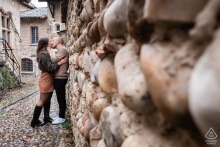 A couple embraces on a cobblestone street in the medieval village of Pérouges, surrounded by historic stone buildings.
