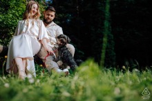 In Budakeszi, Hungary, a couple stands together with their dog, shown in an engagement portrait that includes the pet as part of the scene.