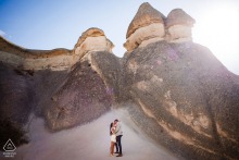 Set in Göreme, Nevşehir, Turkey, a couple is photographed during a Cappadocia pre-wedding session, with the distinctive landscape forming a natural background in this wide environmental portrait.