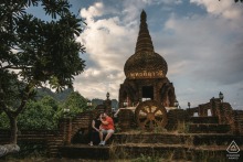 A couple poses gracefully on the ornate stone stairs in front of a traditional temple in Thailand, beautifully blending architectural grandeur with their personal love story for these portraits.