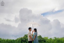 Shanwei pre-wedding engagement portrait of a couple beneath a clear umbrella after the rain, with dramatic storm clouds giving way to blue skies.