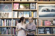 Pre-wedding engagement portrait of a couple browsing books together inside a stylish bookstore in Bangkok, Thailand.