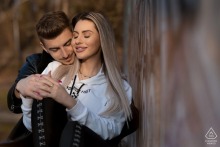An engaged couple shares a quiet embrace during a pre-wedding portrait session in Bucharest, Romania, as the groom gently holds his fiancée's hand.