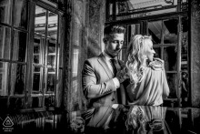 Black and white pre-wedding engagement portrait of a couple framed by ornate architecture and reflections in Bucharest, Romania.