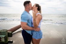 A couple shares a romantic kiss on Sea Isle City Beach while the bride-to-be proudly shows her engagement ring in Sea Isle City, New Jersey.