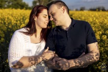 An engaged couple shares a quiet embrace in a field of golden flowers during a pre-wedding portrait session in Vecsés, Hungary.