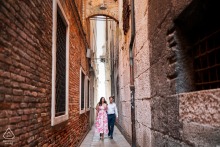 A couple walks hand in hand through a narrow street in Venice, Italy, during a romantic pre-wedding engagement photo session.