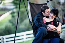 Engaged couple cuddles on a wooden swinging seat in San Jose, California, creating a relaxed and intimate pre-wedding engagement portrait.