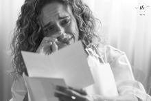 The bride, at VIP Grand Lisboa Hotel in Lisboa, Portugal, wipes away tears as she reads a heartfelt letter from the groom, cherishing his words before the ceremony begins.