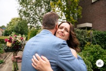 The bride and groom share a powerful embrace outdoors in the Netherlands, the bride clutching her bouquet and displaying profound emotion, marking a moment of deep love and relief.