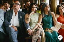 During the wedding ceremony at Prince Albert Pub in Camden, London, the bride’s parents tenderly hold hands as their other daughter, seated between them, is visibly moved to tears.