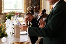 At Stowe House, the groom reacts tearfully as he listens to his father's heartfelt speech, displaying deep emotion and connection during the wedding celebration.