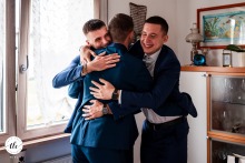 In Udine, Friuli Venezia Giulia, Italy, the groom warmly embraces his witnesses during preparations, highlighting close friendship and support in the moments leading up to the celebration.