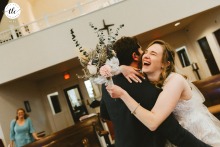 In St Bridget of Ireland Church, Berryville, VA, a bride and groom share hugs and laughter as the bride’s mother lovingly looks on, sharing in their happiness.