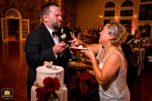 In Virginia at Poplar Springs Manor in Warrenton, the bride playfully smashes cake into the groom's face, causing it to fall off as they both share a joyous laugh.
