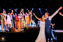 Wedding photograph from a reception party at Arka Barut-Antalya, Turkey, showing the bride and groom standing together while guests stand behind them, all with arms raised.