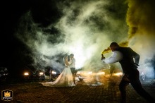 At the Farmhouse Hotel in Guernsey, a groomsman adds a dramatic touch to the evening portrait session of the bride and groom with a colorful smoke bomb. 