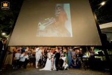 At Villa Calini, guests watch a video of the groom's childhood. The groom reacts with excitement. The reception is at Ristorante Alessandro Cappotto in Coccaglio, Italy.