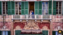At Villa Faraggina, Savona, the bride and groom pose for a portrait on the balcony of an old-world building, exuding timeless elegance.