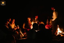 At Barn Drift, North Norfolk, UK, wedding guests share a warm, silhouetted moment by the fire pit, creating a cozy ambiance.