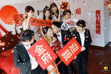 Newlyweds at home in Shanghai, China, celebrate joyfully with friends, confetti falling, and festive red “We’re getting married” signs.