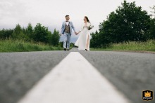 Bride and groom walk down a sunny street near their hotel in Poland, captured during a brief wedding day photo session.