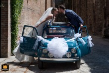 At the walls of Montagnana, Padua, Italy, the couple shares a unique kiss over the roof of a vintage car. Surrounded by historic charm, this playful, romantic portrait beautifully blends timeless love with nostalgic elegance on their special day.