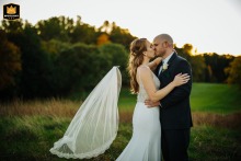 In Rockland County, New York, a couple shares a tender kiss during golden hour. As the sun glows softly, the bride’s veil slips free, creating a candid, joyful image that captures the spontaneity and romance of their day.
