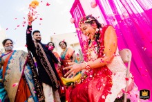 In Schaumburg, IL, the bride sits radiant during her haldi ceremony, a cherished Indian wedding tradition. Loved ones shower her with flower petals, filling the air with color and joy, celebrating love, blessings, and new beginnings.