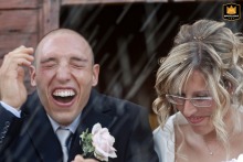 Closeup of a joyful couple getting showered with rice outside a church in San Pietro in Trento, Italy.