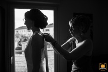 Mother of the bride helping her daughter get ready in a bedroom. They are focused on the task.