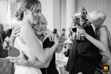 A Bride's Loving Embrace: A Family Hug on a Rushton Hall Wedding Day Bride in white dress hugs her mum while her sister hugs their dad at Rushton Hall wedding.