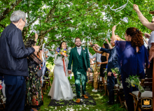 A wedding photographer captures a joyful moment at the Domaine de la Compagnie des Campagnes. The image shows the newlywed couple exiting their secular ceremony to a flurry of applause from their celebrating guests.