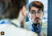 Captured at Koury Farms in Auburn, Georgia, a WPJA wedding photographer frames a groom's quiet, reflective moment. The over-the-shoulder shot focuses on the man's serious expression as he meticulously adjusts his tie in the mirror before the ceremony.