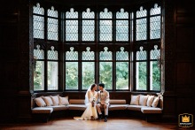 Hempstead House: A Portrait of Joyful Love in Light Portrait of a bride and groom sitting in a brightly lit room with two levels of windows at Hempstead House.