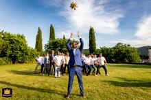 At an estate in Tarn-et-Garonne, the groom is playfully tossing the bride's bouquet high into the air, creating a humorous and inverted twist on a traditional moment during the wedding celebration.