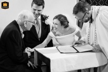 Bride reaching for her grandfather’s hand during the signing of the register at Houghton on the Hill Church.