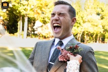 Groom laughing as his bride pins a boutonniere with a stuffed shrimp onto his jacket on a golf course in Roswell, Georgia.