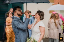 At the Museum Huelsmann in Bielefeld, Germany, the wedding couple creatively shares a bottle of champagne while holding a large umbrella provided by a local funeral home.
