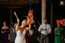 Avonlea Farms, VA - Bride swings a stick at a festive, brightly-colored piñata while cheers are enthusiastic behind her during the reception.