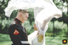 Bride Flips Veil For Kiss With Groom At Ivory Acres, Both Smiling Under Tree Canopy At Ivory Acres Wedding Venue in Frewsburg, NY, the bride playfully flips back her veil for a kiss with the groom. Both smile joyfully under a canopy of trees during their after-ceremony portraits.