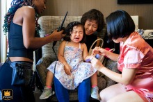   In Philadelphia, a flower girl is gently assisted by her loved ones as she gets ready for the wedding, their caring hands helping her prepare for the big moment.