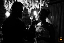 At Canto Verde in São Paulo, Brazil, the newlyweds with glasses raised to toast, smile broadly, acknowledging the warm energy and support of friends and family around them.
