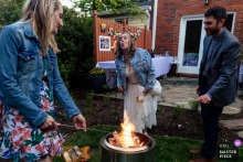 A bride smiles as she prepares Smores for her intimate backyard wedding celebration in Bethesda