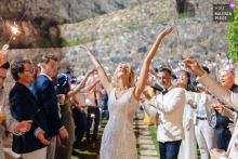 In this image, captured by an Italian wedding photographer at Villa Hamalia in Sicily, the bride is embraced by joyful guests as she celebrates, her arms raised to the sky