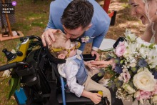 In the reception venue in Saint-Brieuc, Cotes-d'Armor in Brittany, the wedding photographer captures a heartwarming moment as a child with a disability brings the wedding rings to his parents